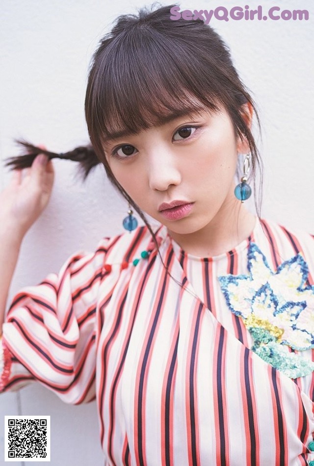 A woman wearing a striped shirt and blue earrings.