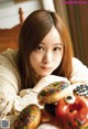 A young woman sitting at a table with a bunch of donuts.