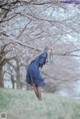 A woman in a blue dress standing in a field of grass.